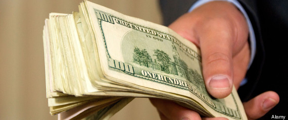 a hand giving a stack of 100 dollar bills